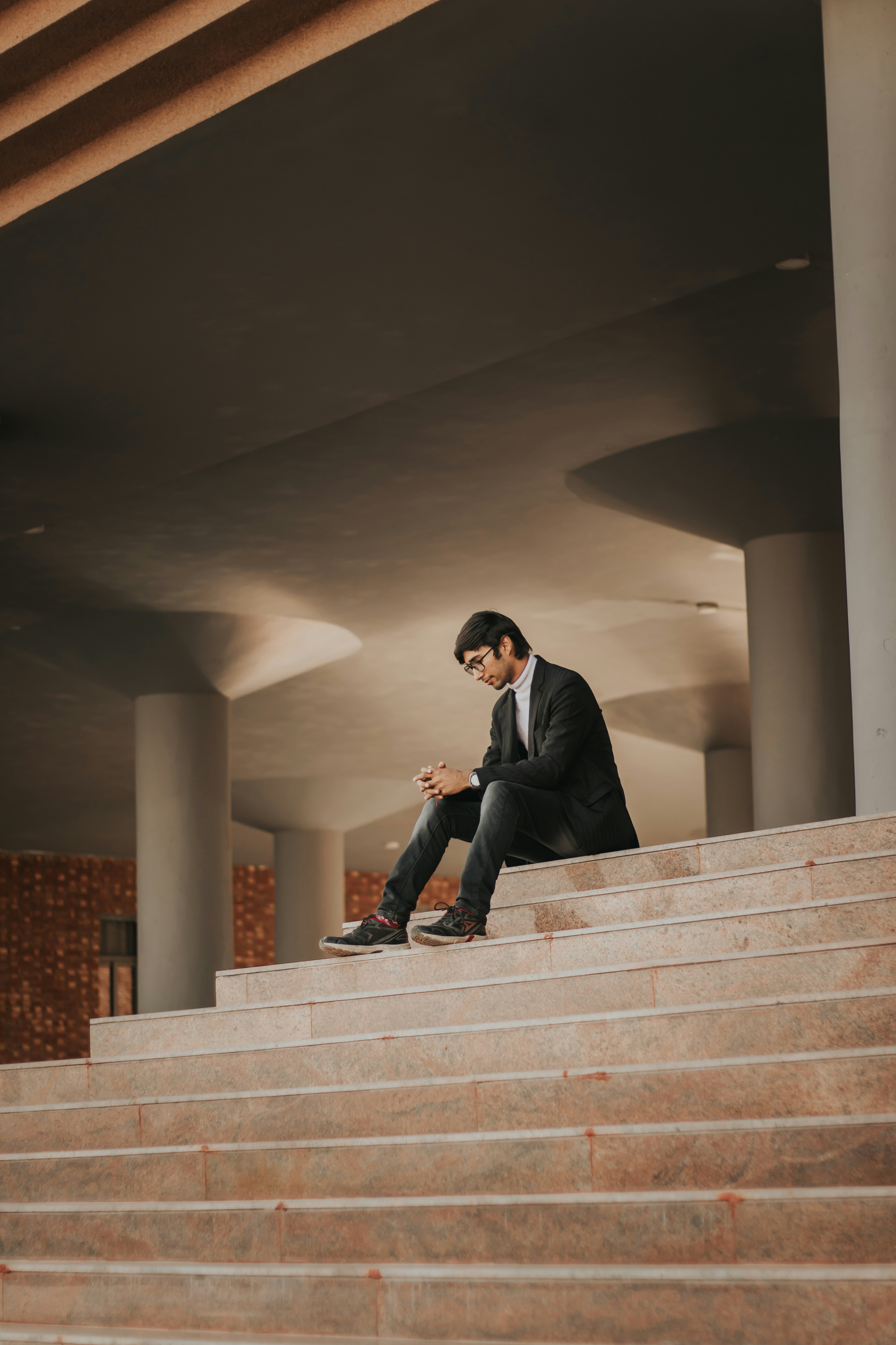 man in black suit sitting on white concrete staircase